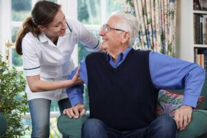 Older couple shares a meal in an accessible assisted living apartment while a caregiver provides discreet support.