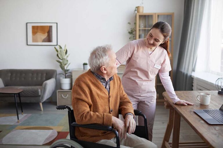 Older adult and family member visiting in a bright assisted living common room with a sign-in desk nearby